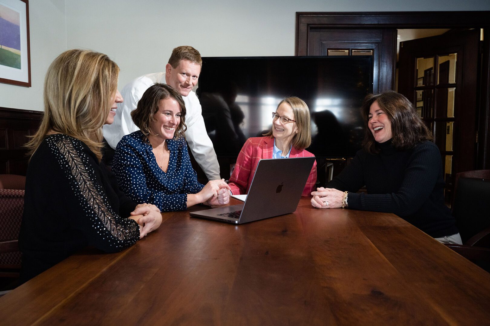 Five employees from the Brattleboro office sharing a laugh around a computer